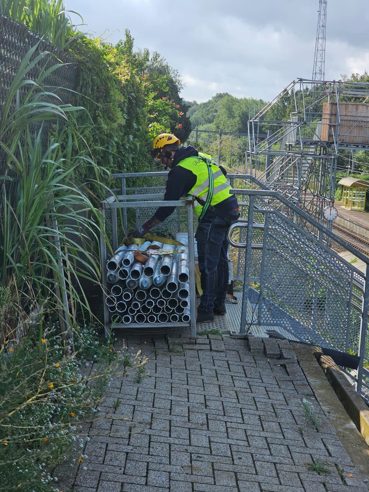 Medewerker bij een kooi met verzinkte palen met schroefdraad, langs het spoor