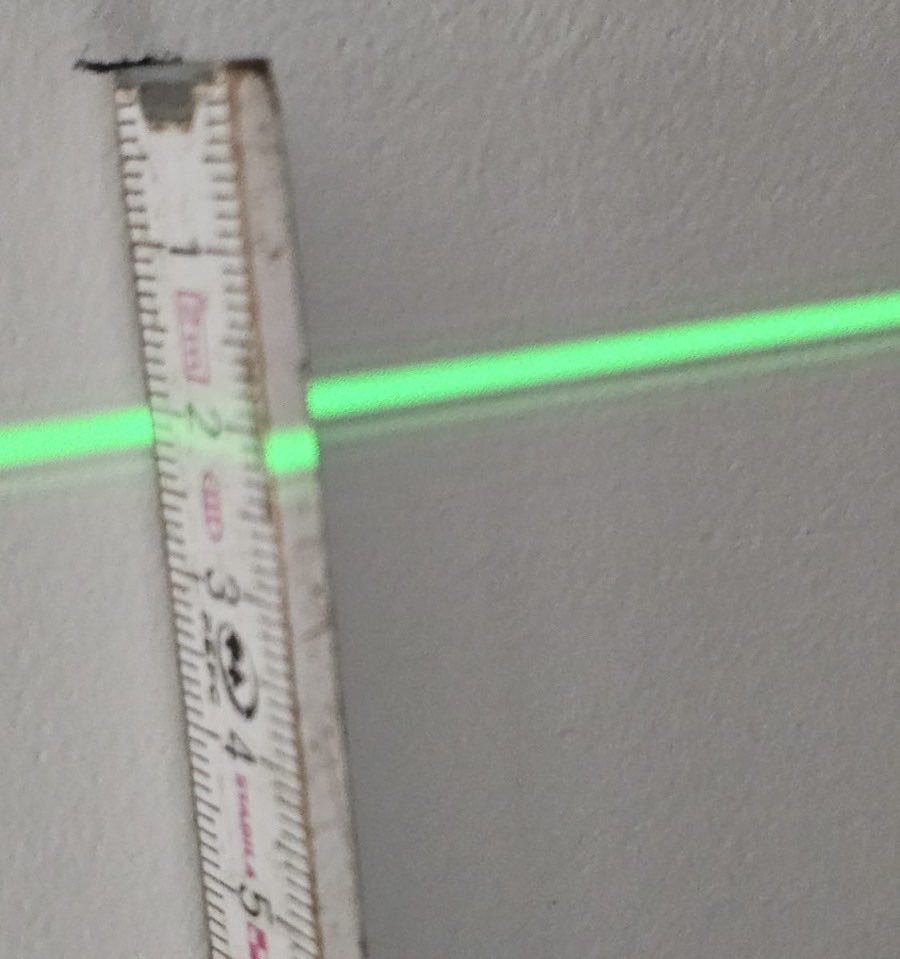 Ligne laser verte sur un mètre contre un mur intérieur