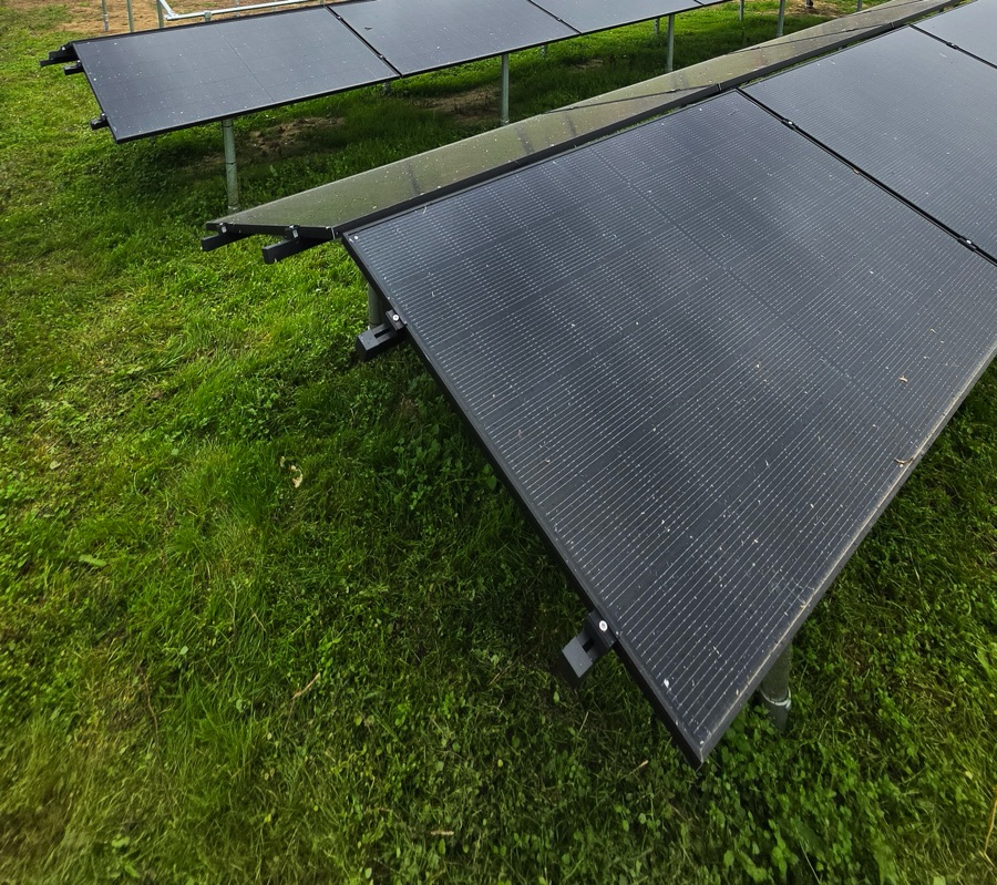 Rijen zonnepanelen op een stalen frame in een weide