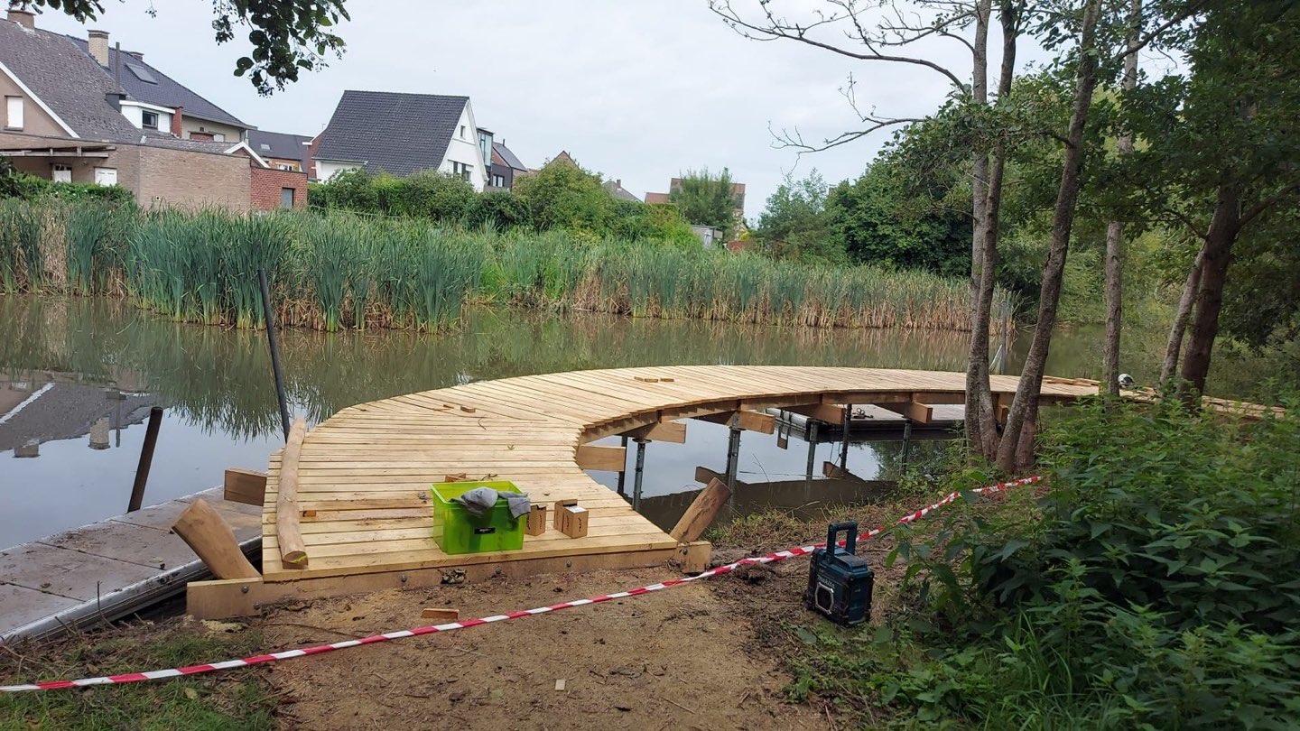 Gebogen houten vlonder op schroefpalen boven het water in Zottegem