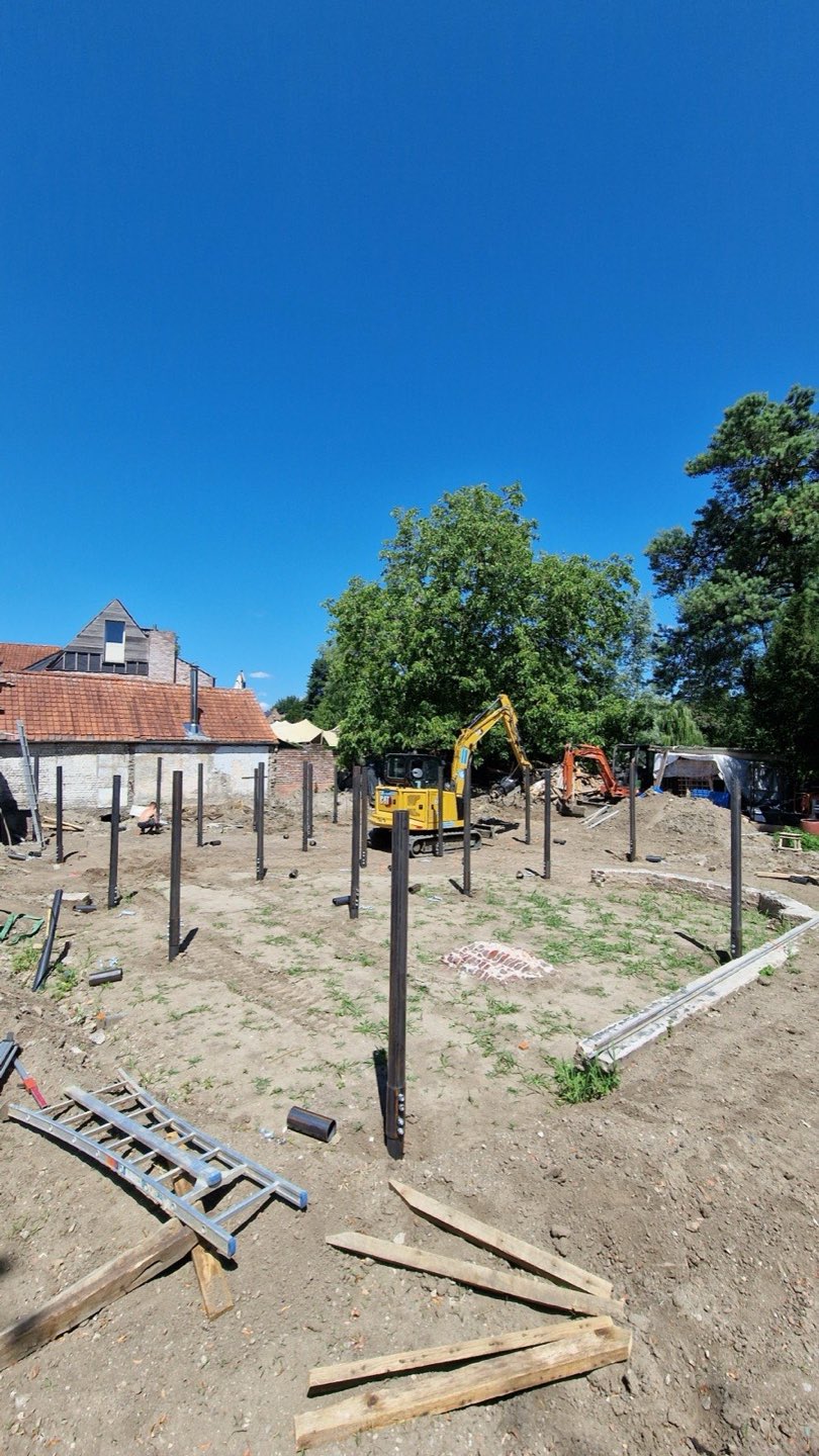 Raster van schroefpalen op een bouwwerf tussen woningen
